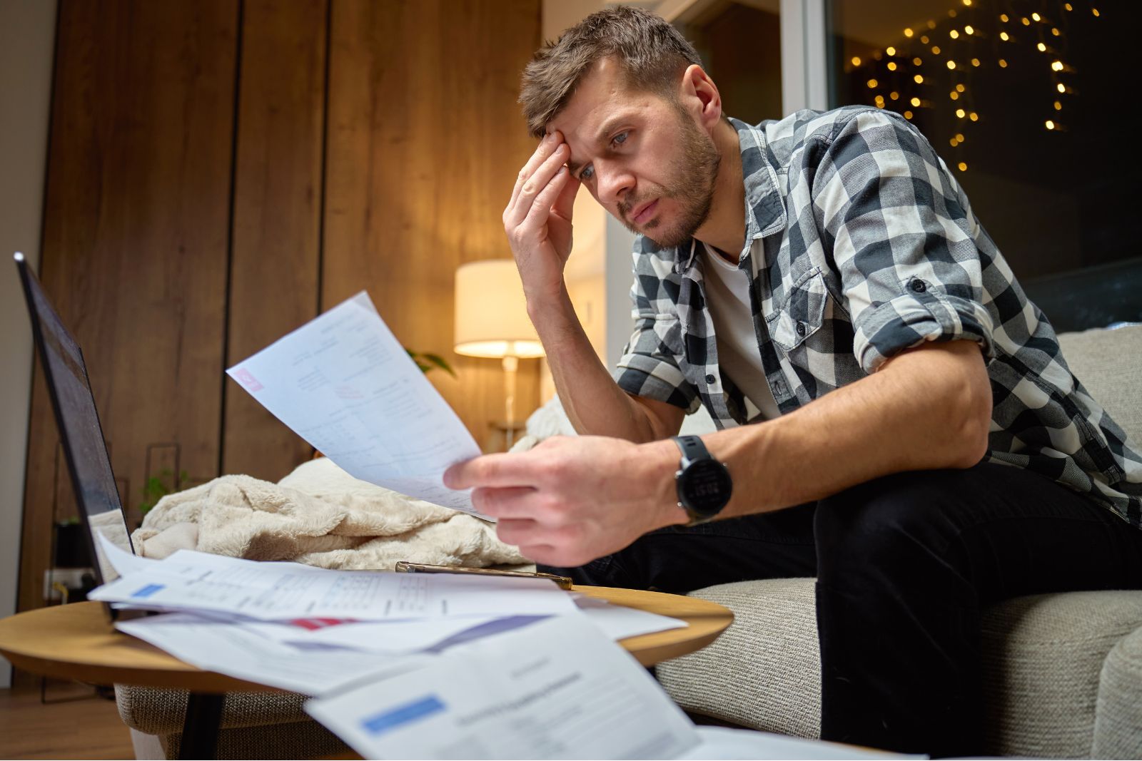 Man looking stressed at home with phone and daily responsibilities nearby