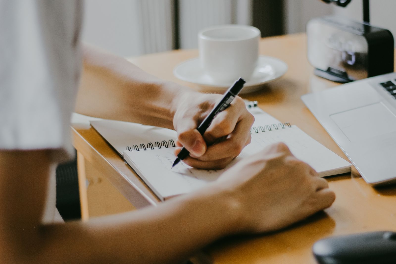 Adult making notes in a notebook at a home table