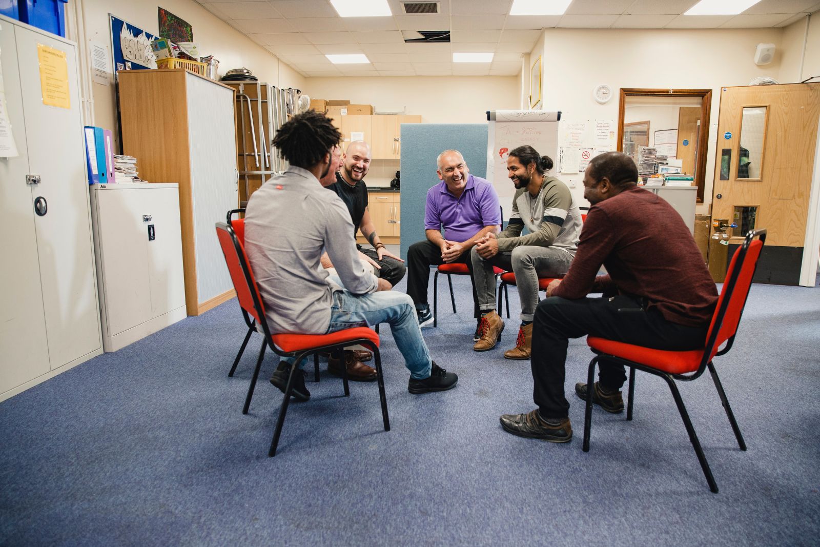 Small group of adults seated in a circle in a community room